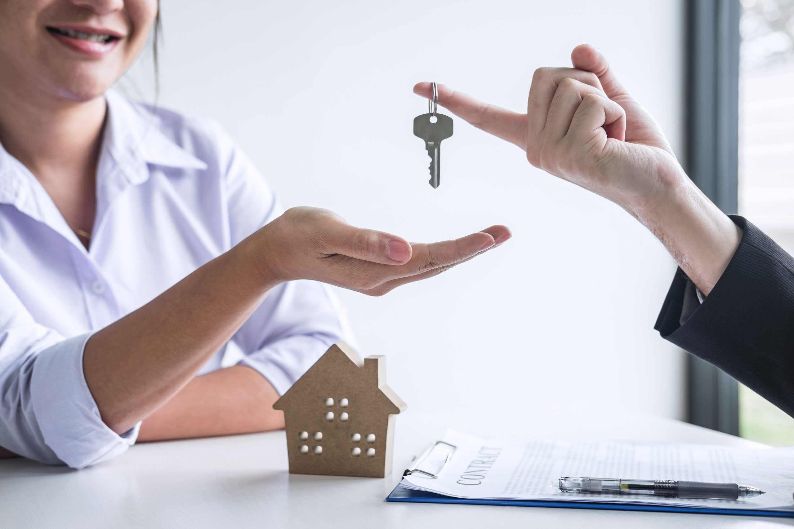 Estate agent giving house keys to client after signing agreement